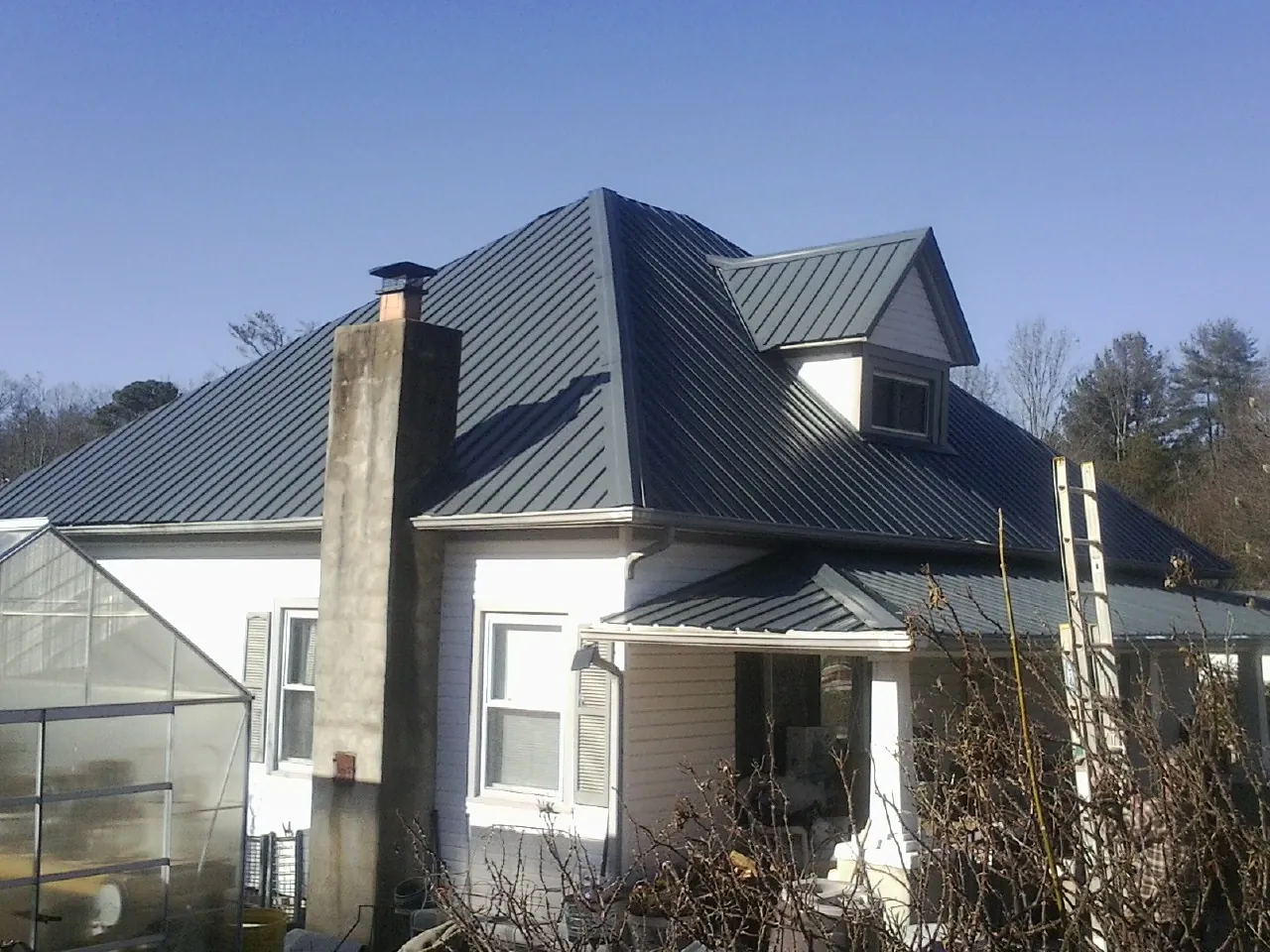 Dark blue standing seam metal roof on a white farmhouse with dormer — Slate & Tile Roof Repair by Roofing Brothers in Elberton