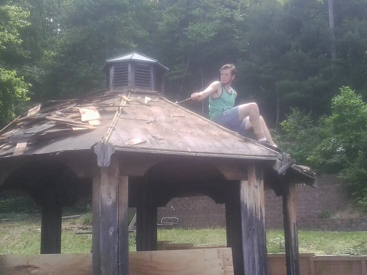 Tearing the old roof off a wooden gazebo before new shakes in Elberton
