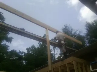Carpenter setting a ridge beam over a new addition frame — Ice Dam Removal by Roofing Brothers in Elberton