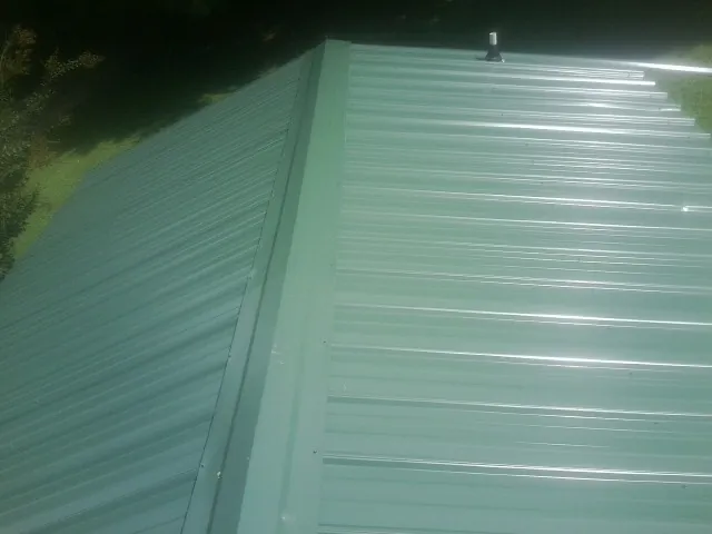 New green metal panels meeting at the ridge of a roof — Flat Roof Repair work by our crew in Elberton