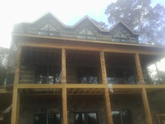 Dormers and porch framing on a large log home under construction — Roof Coating work by our crew in Elberton