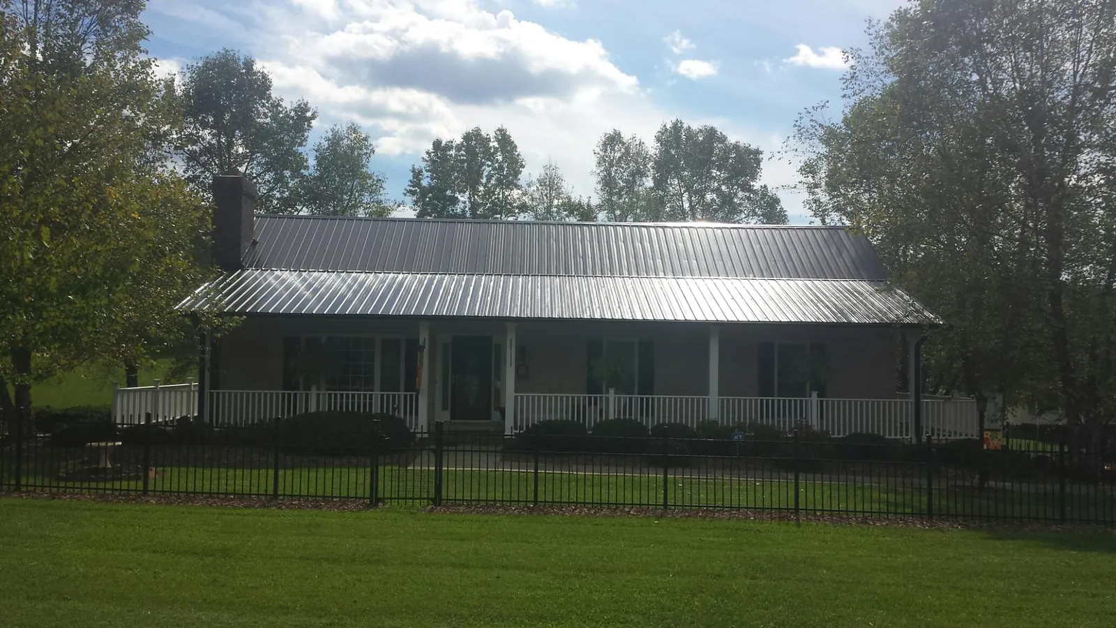 Gray metal roof on a brick ranch with a full width front porch — Gutter Guard Installation work by our crew in Elberton