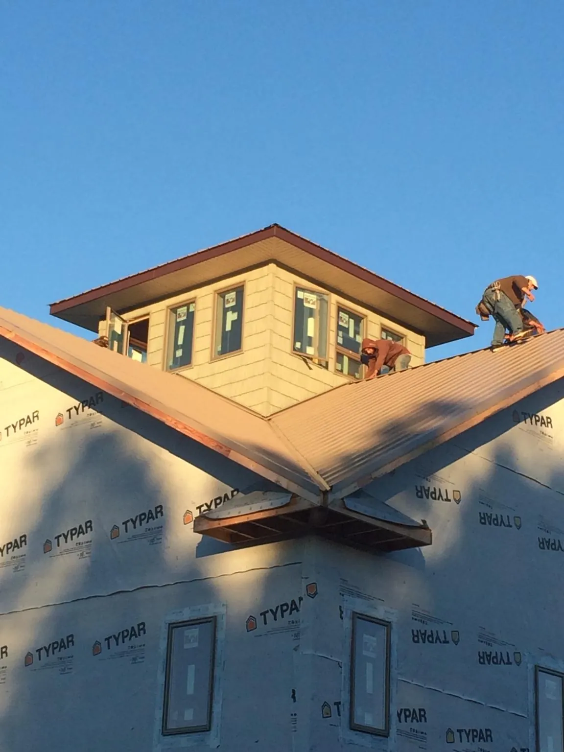 Roofers working around a rooftop cupola on a new metal roof at sunset — Roof Waterproofing in Elberton by Roofing Brothers